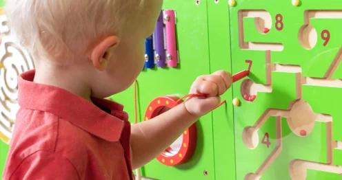 Anaokulu sınıfında duvara monte edilmiş renkli duvar aktivite oyunlarıyla oynayan çocuklar