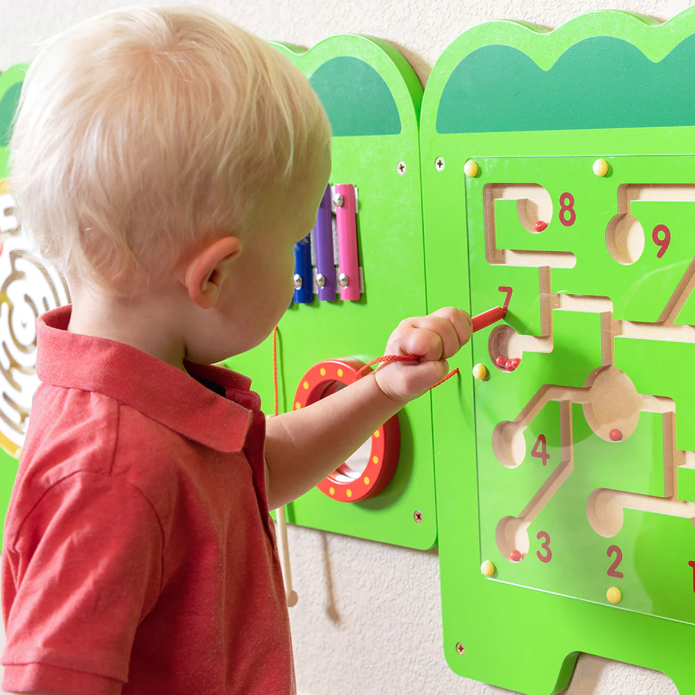 Anaokulu sınıfında duvara monte edilmiş renkli duvar aktivite oyunlarıyla oynayan çocuklar