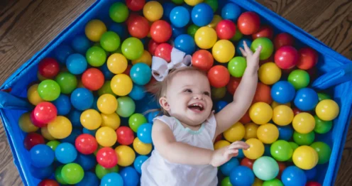Renkli havuz topları arasında gülerek oynayan küçük çocuk top havuzunda duyusal gelişim